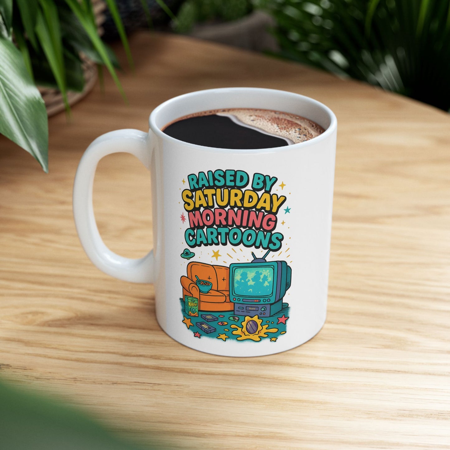 White ceramic mug with retro-style cartoon design featuring a CRT TV, cereal bowl, and couch, 90s nostalgia aesthetic.
